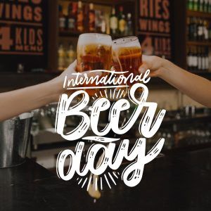Duas pessoas brindando com os copos de cerveja em um pub